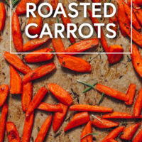Parchment-lined baking sheet of perfect roasted carrots with fresh herbs