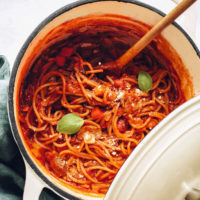 Big pot of vegan spaghetti topped with fresh basil