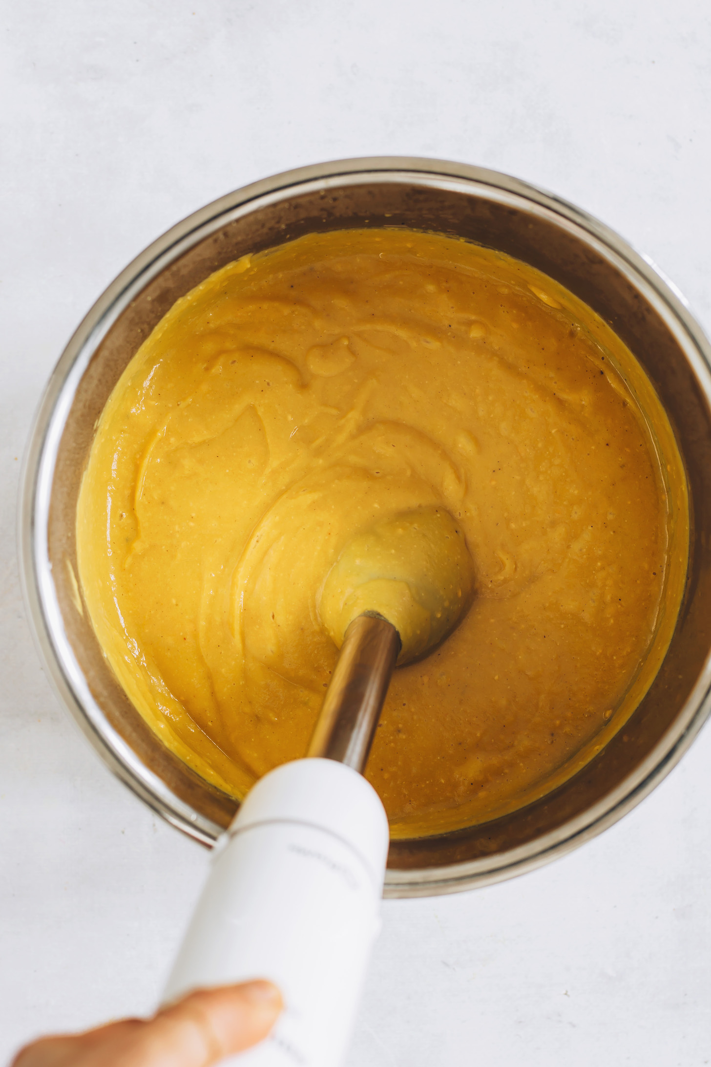 Puréeing creamy sweet potato red lentil soup with an immersion blender