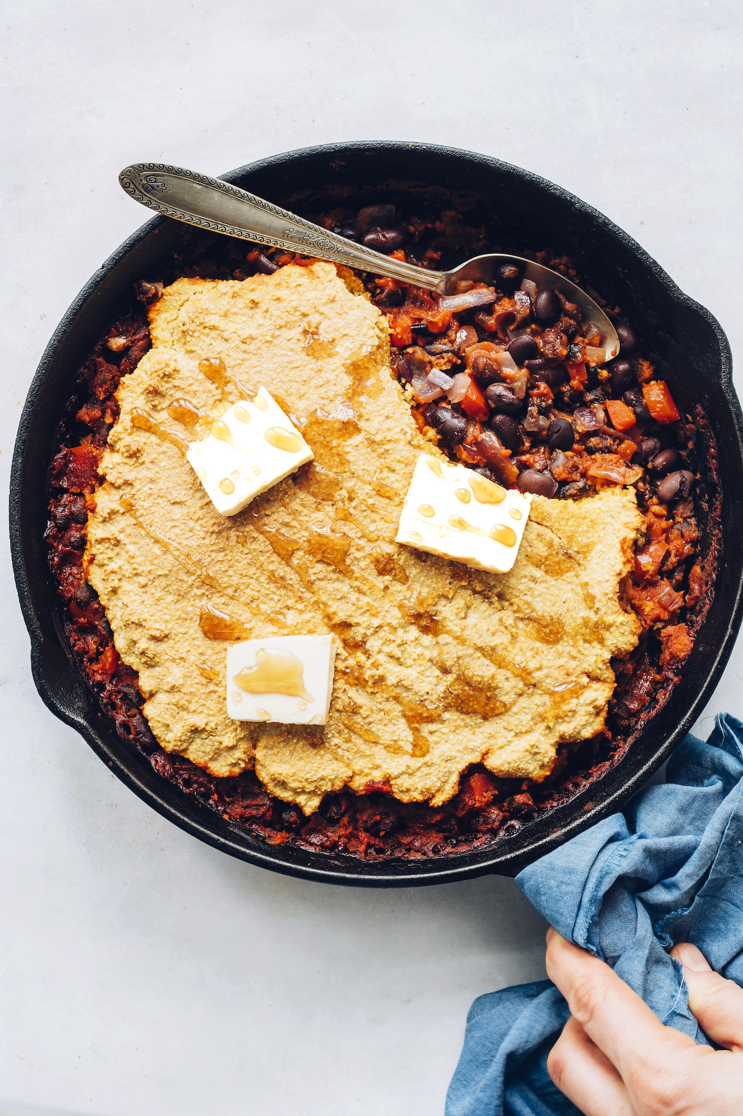 Pan of our Cornbread & Black Bean Enchilada Bake topped with vegan butter and maple syrup
