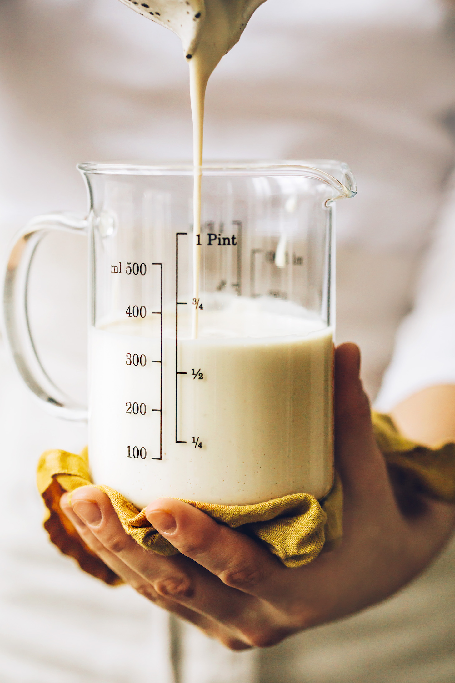 Pouring cashew bechamel sauce into a measuring glass