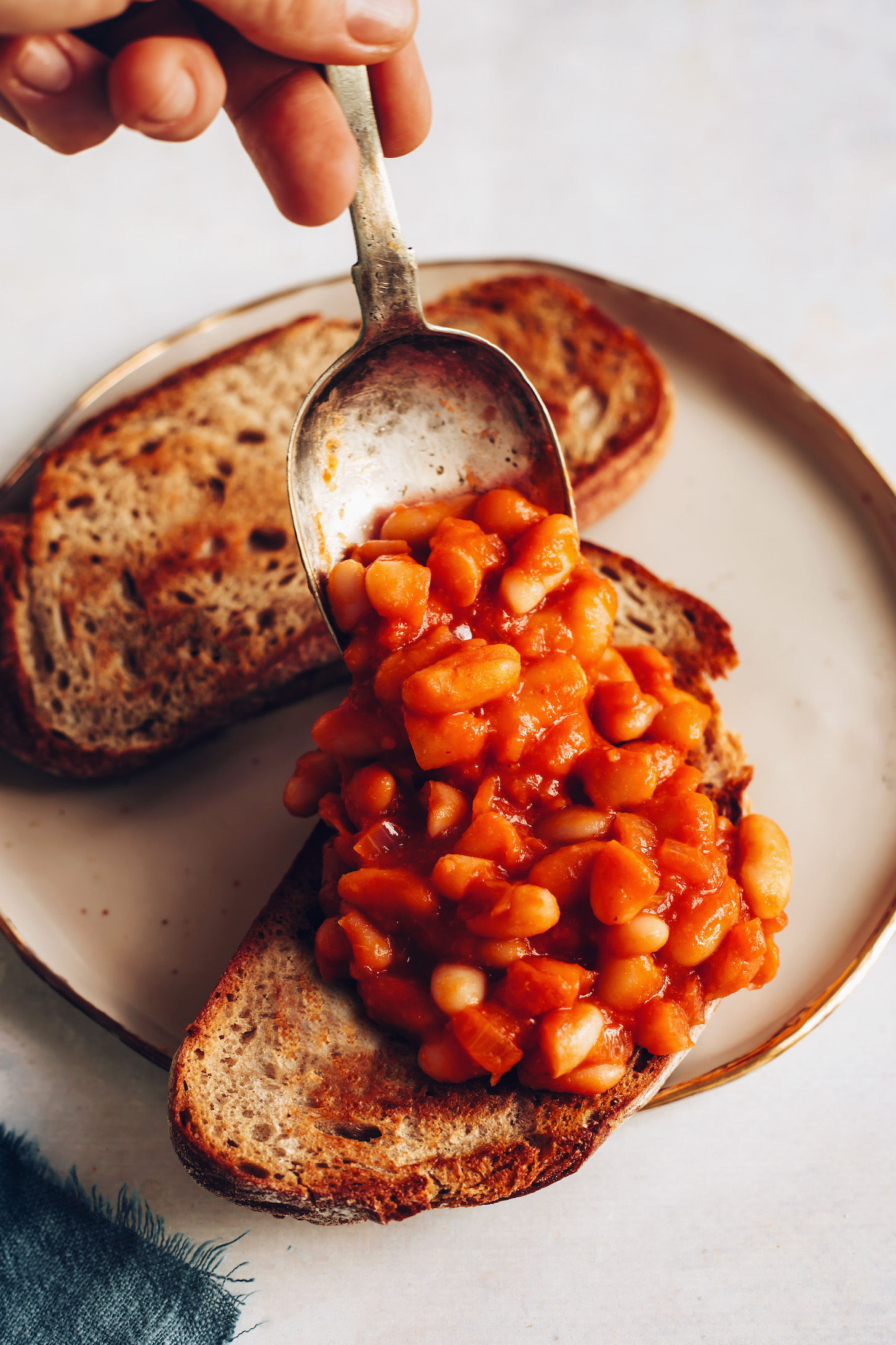 Using a vintage spoon to spread baked beans on toast