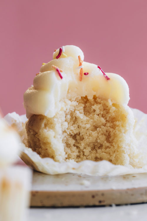 Partially eaten gluten-free vegan vanilla cupcake with buttercream frosting