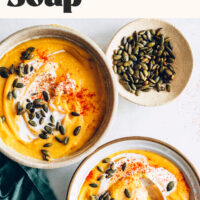 Two bowls of our creamy red lentil sweet potato soup next to a bowl of pepitas