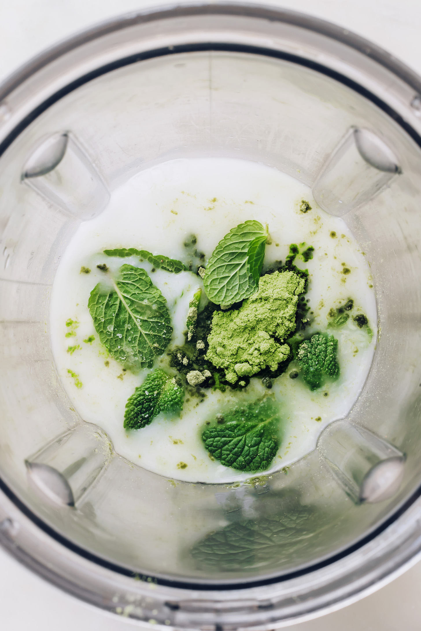 Blender with a date, fresh mint leaves, matcha, coconut milk, sea salt, and water