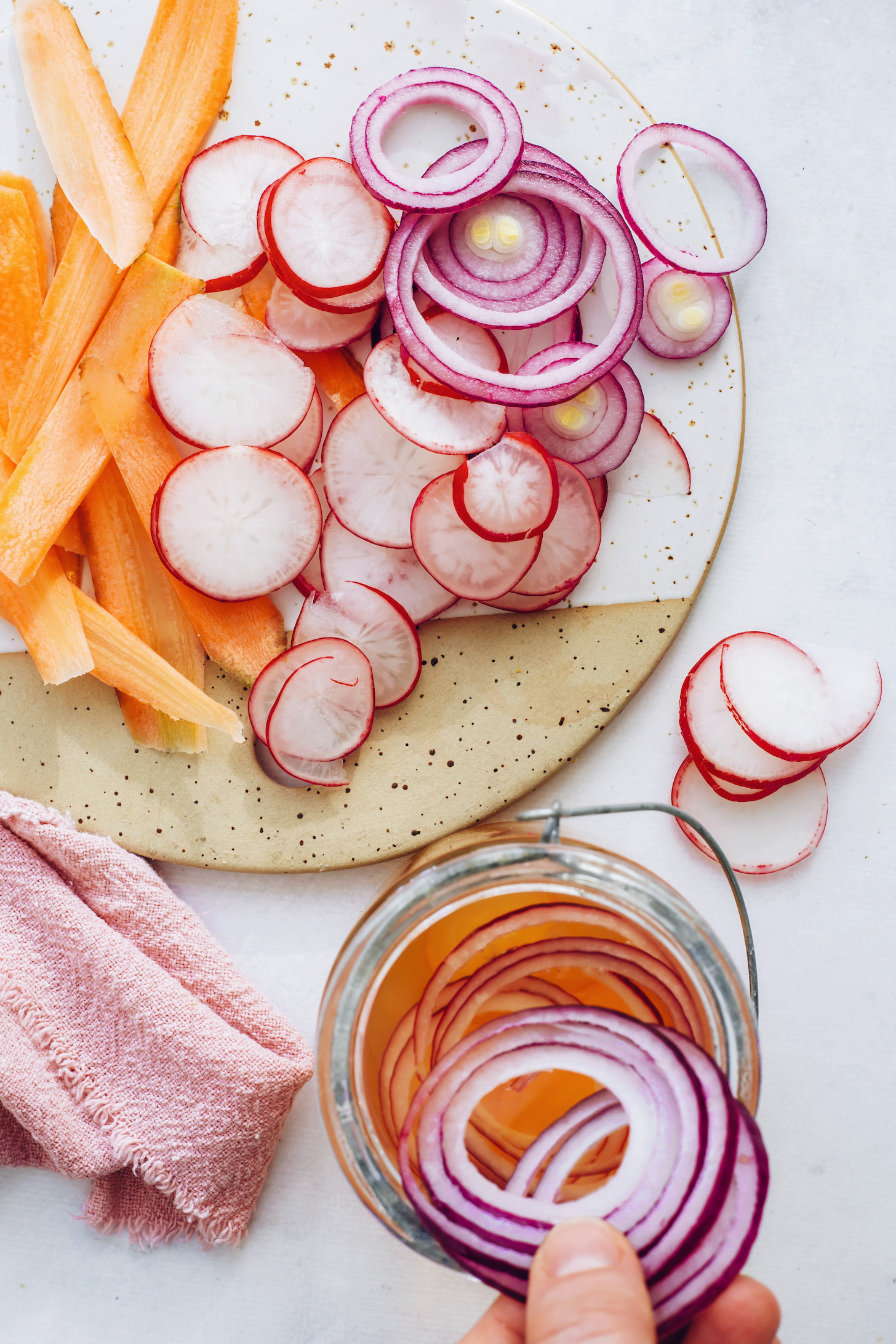 Placing red onion in a jar to make quick pickled vegetables