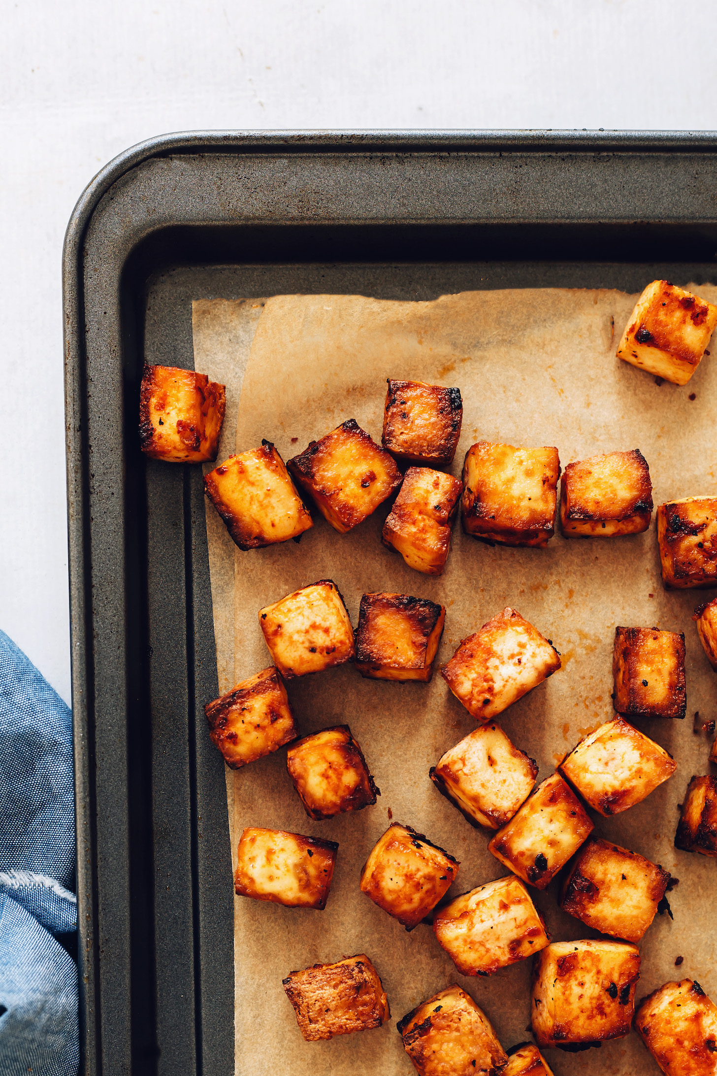 Cubed baked tofu on a parchment-lined baking sheet