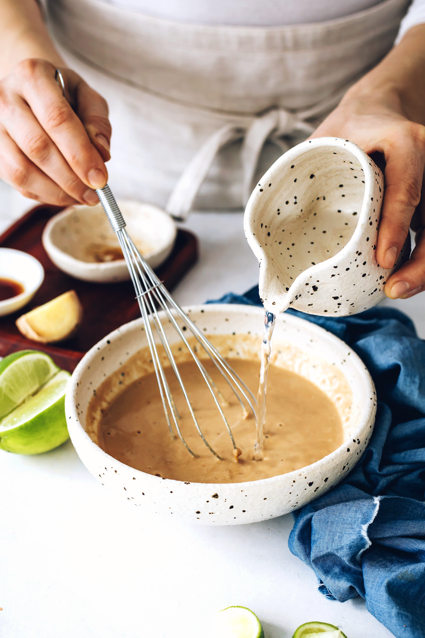 Pouring water into a bowl to thin tahini stir fry sauce