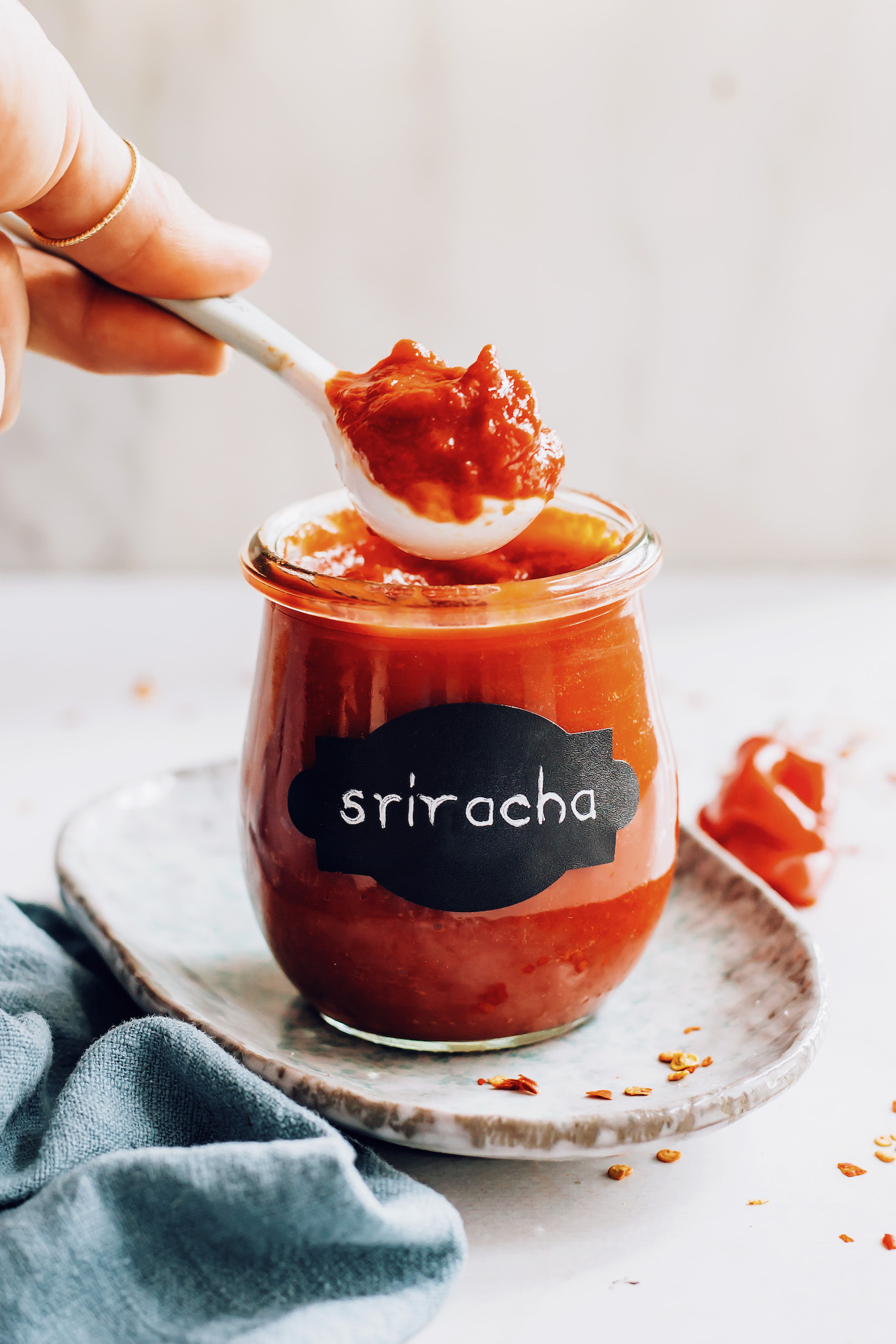 Holding a spoonful of homemade sriracha over a jar