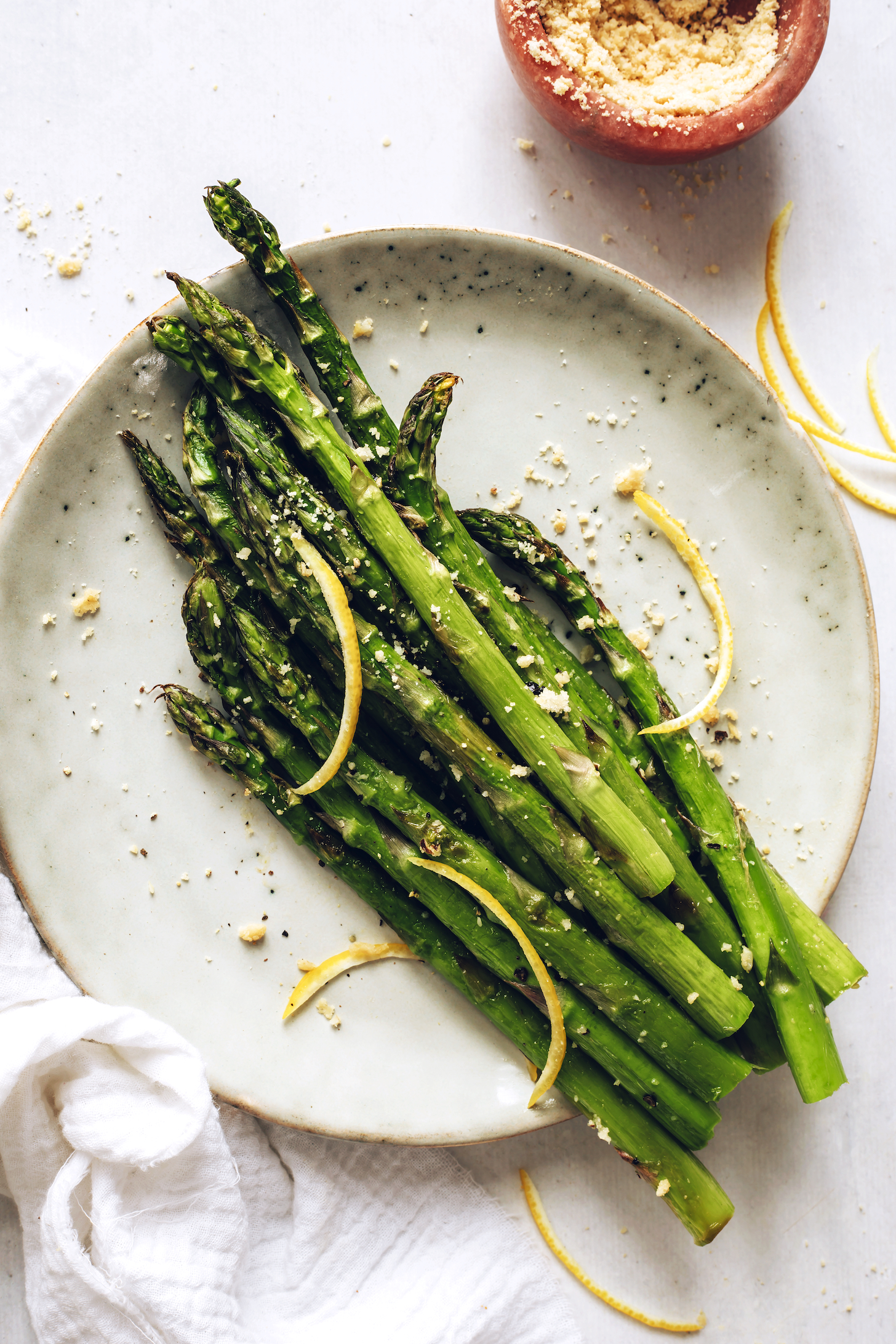 Plate of roasted asparagus with vegan parmesan cheese and lemon