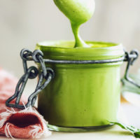 Jar of green goddess salad dressing with some dripping off a spoon