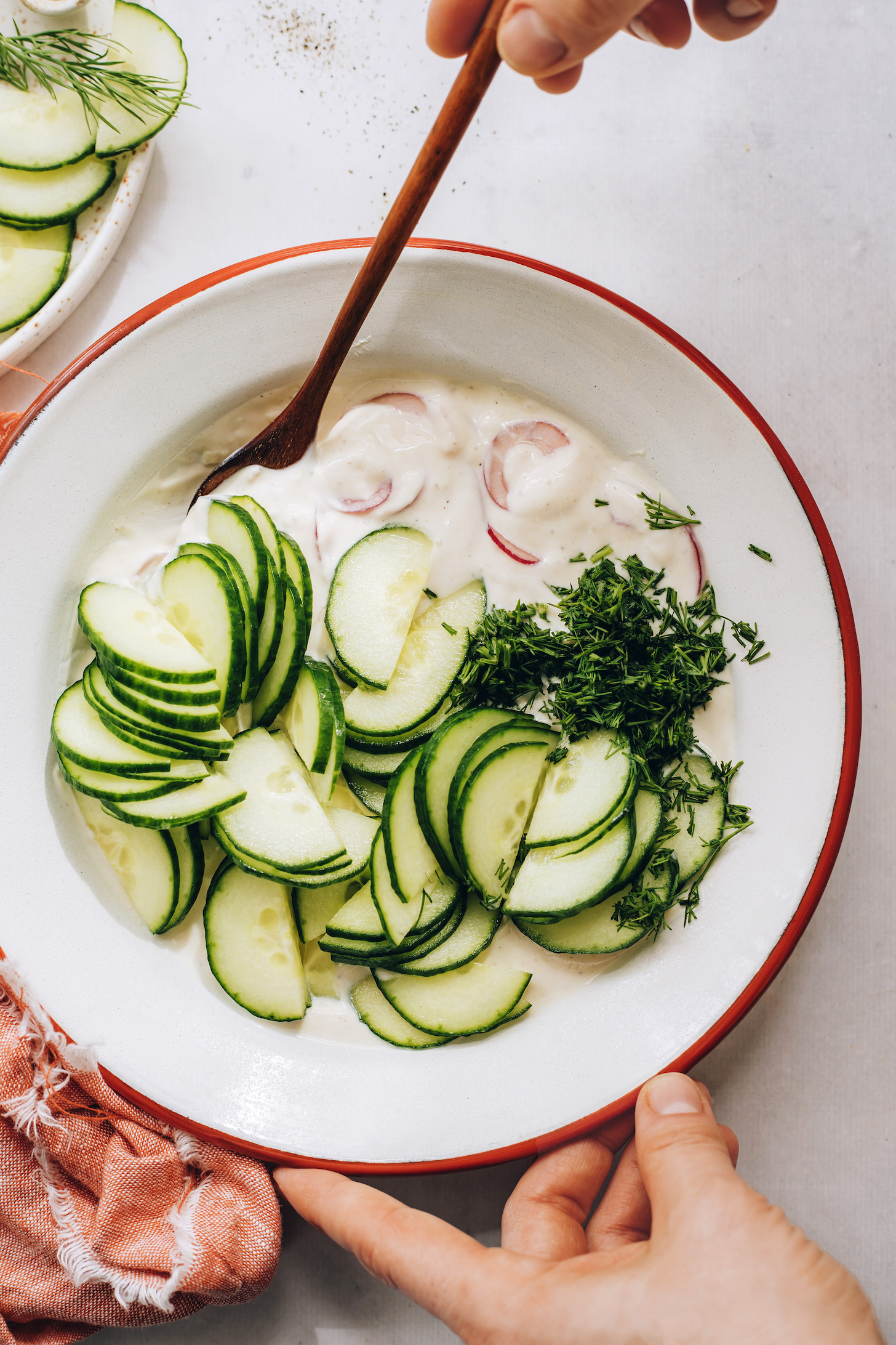 Bowl with sliced cucumber, dill, onion, and creamy vegan dressing
