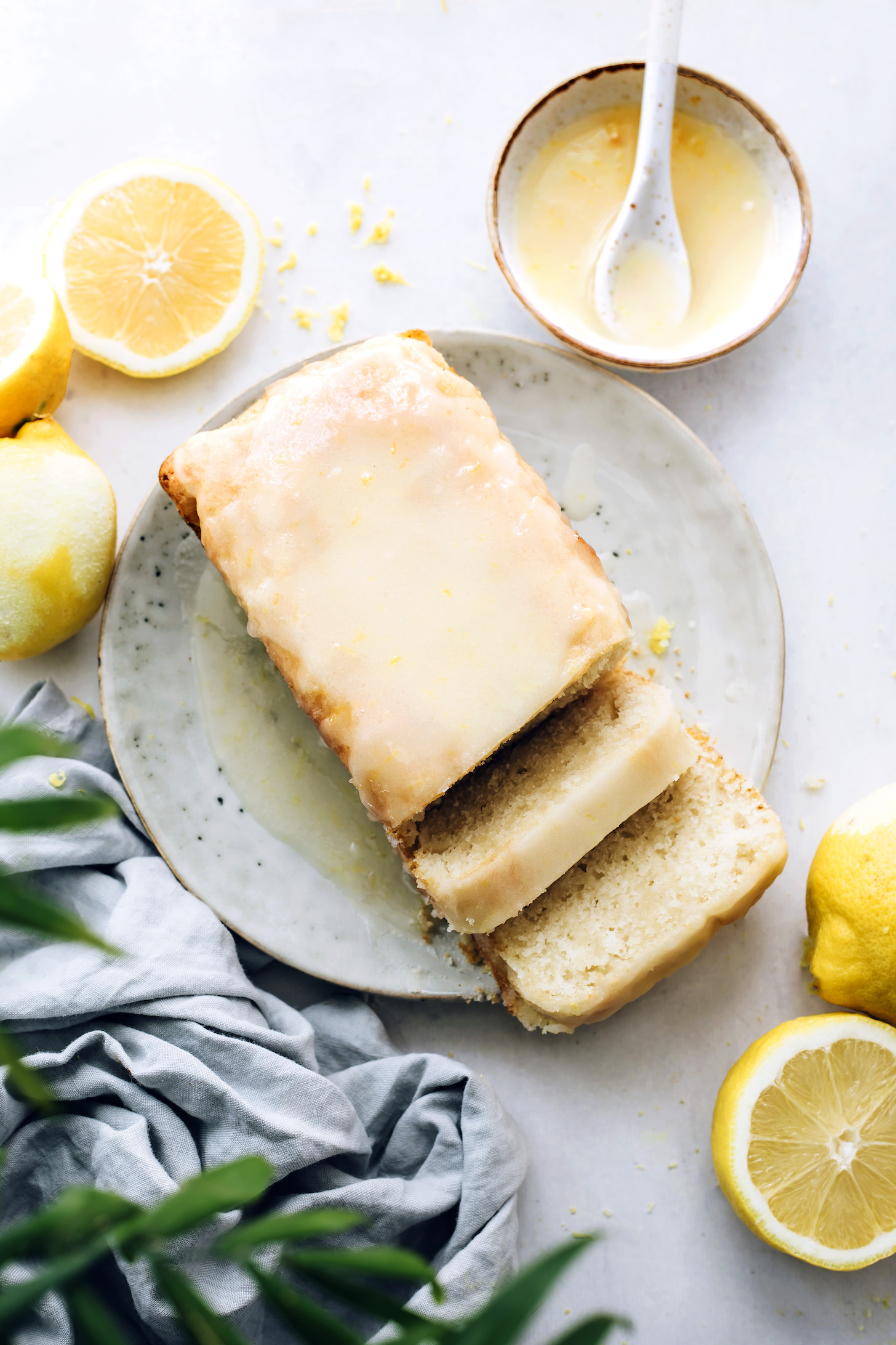 Partially sliced loaf of vegan lemon cake with lemon glaze
