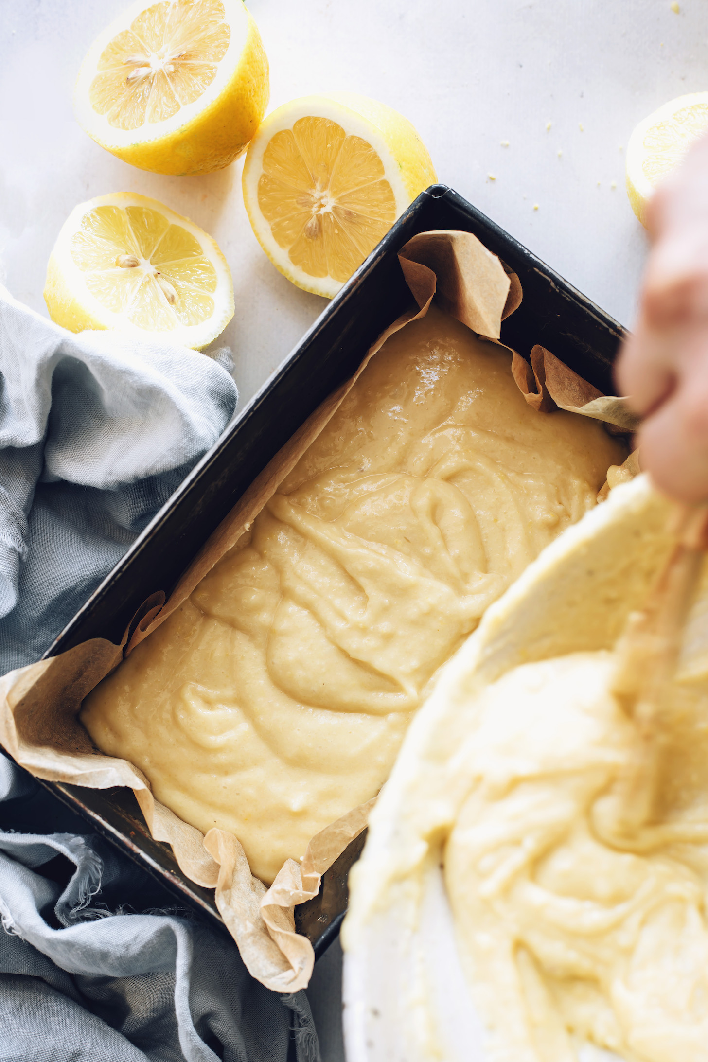Pouring vegan lemon cake batter into a loaf pan