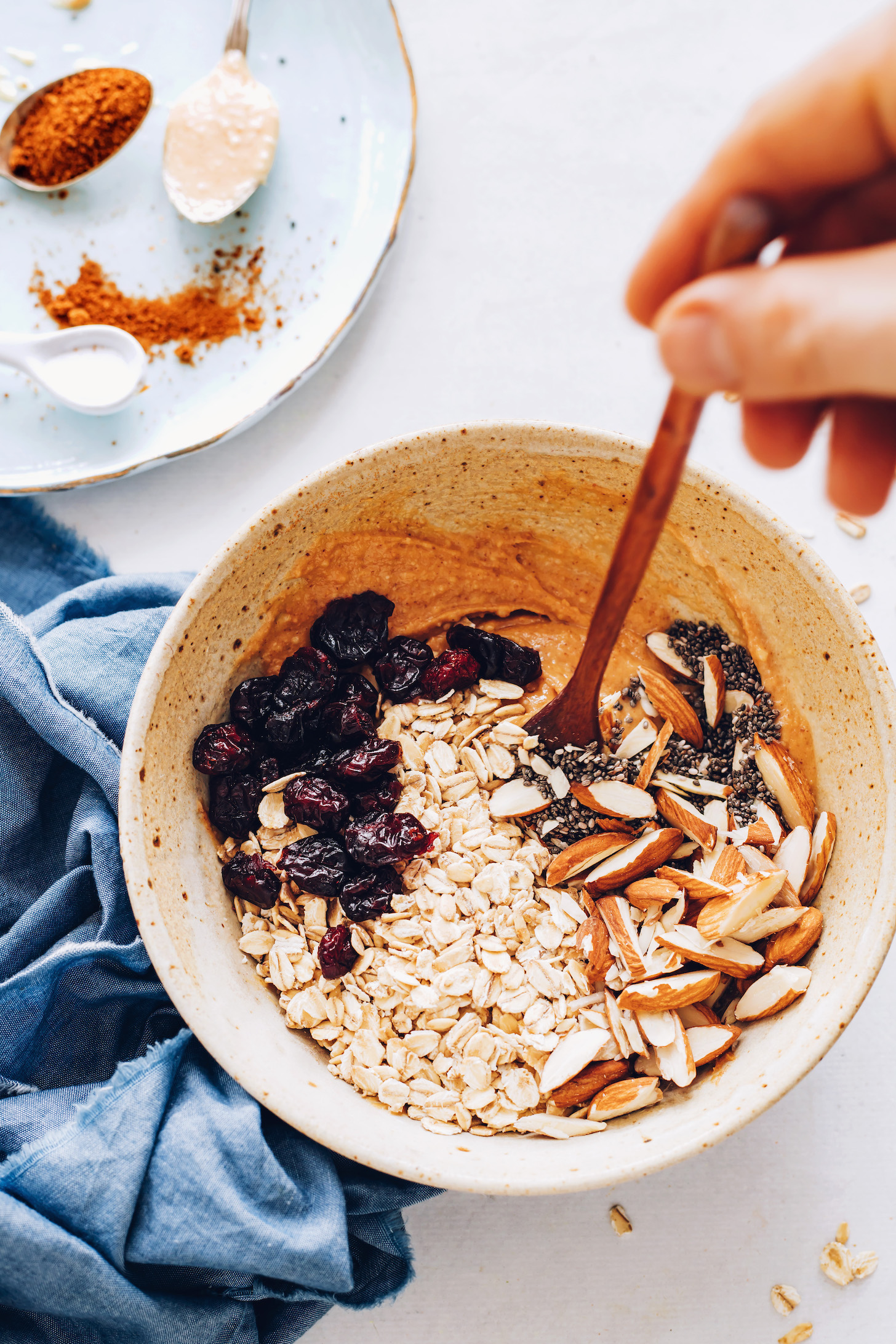 Oats, almonds, chia seeds, and dried cherries in a bowl with the wet ingredients