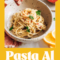 Sprinkling vegan parmesan cheese into a bowl of pasta al limone