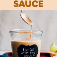 Tahini stir fry sauce pouring off a spoon into a jar