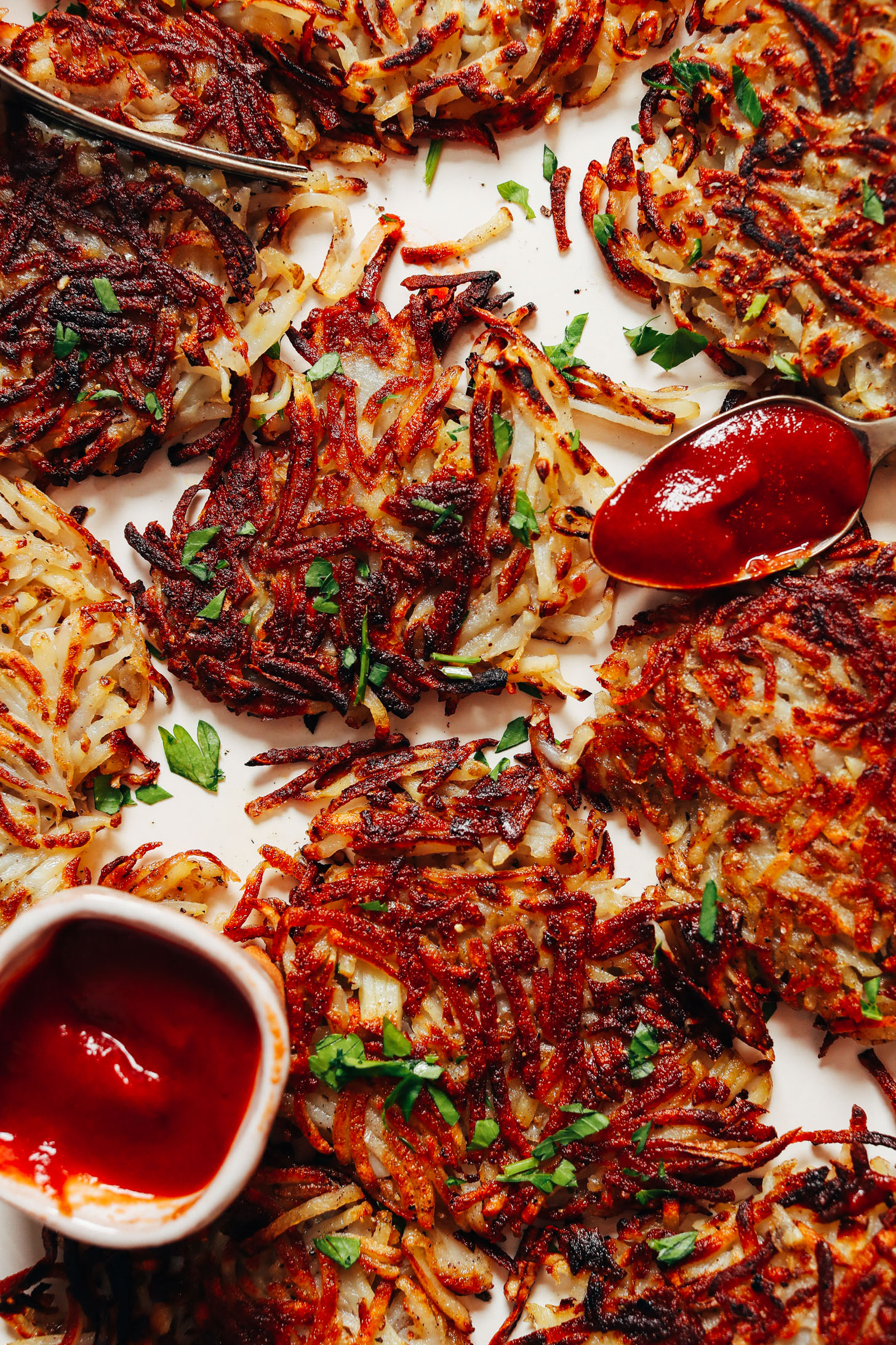 Crispy homemade hash browns topped with parsley and next to ketchup