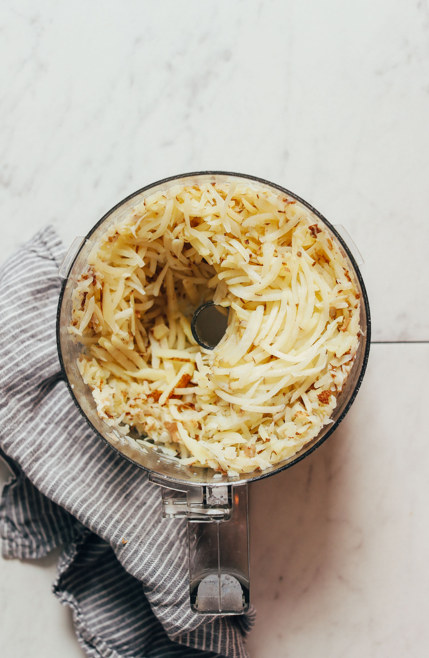 Par-cooked grated potatoes in a food processor