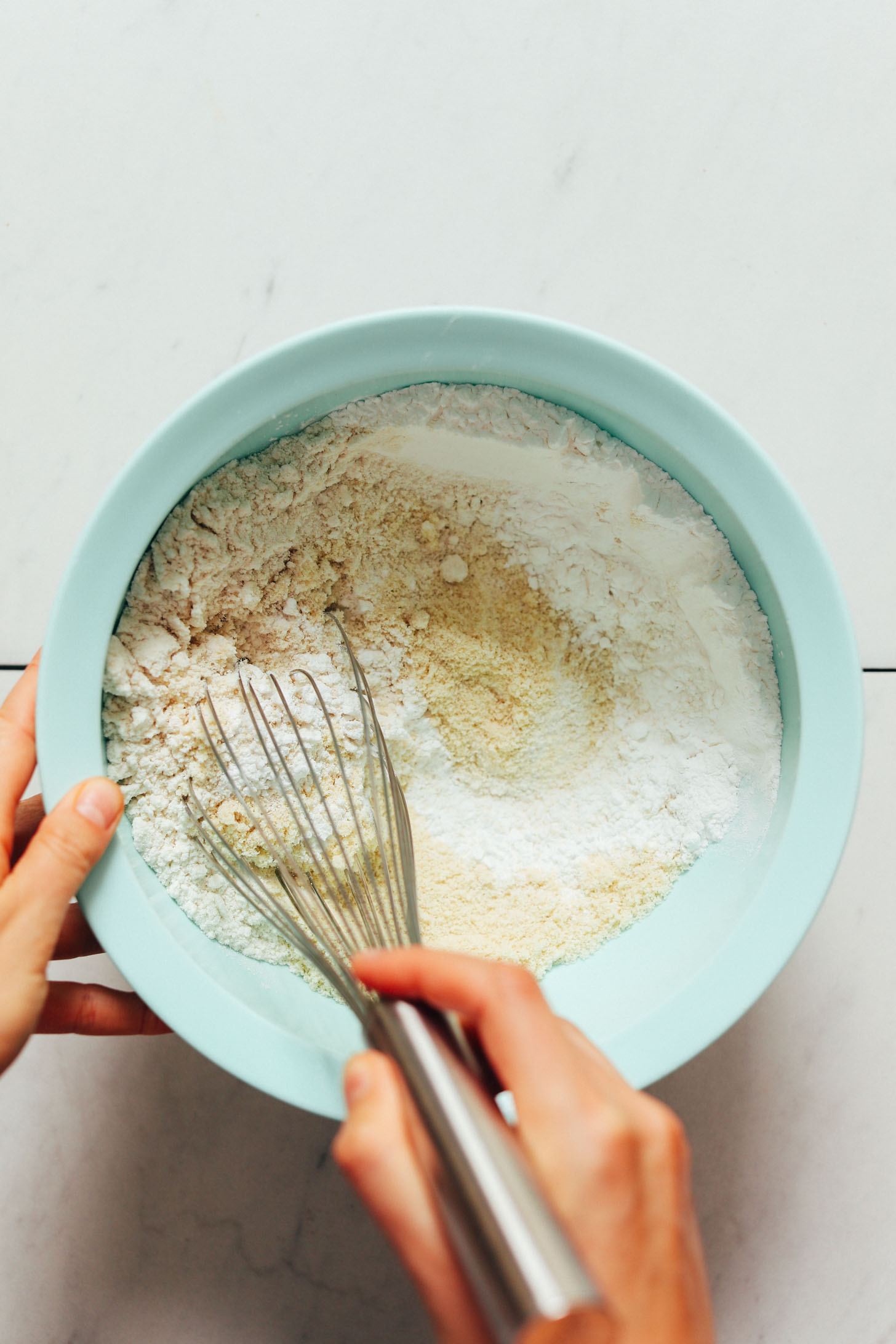 Whisking almond flour, gluten-free flour blend, tapioca flour, baking soda, and sea salt in a bowl
