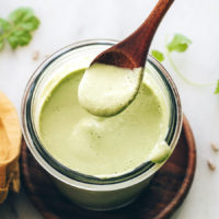 Spoonful of creamy cilantro sunflower seed dressing over a jar