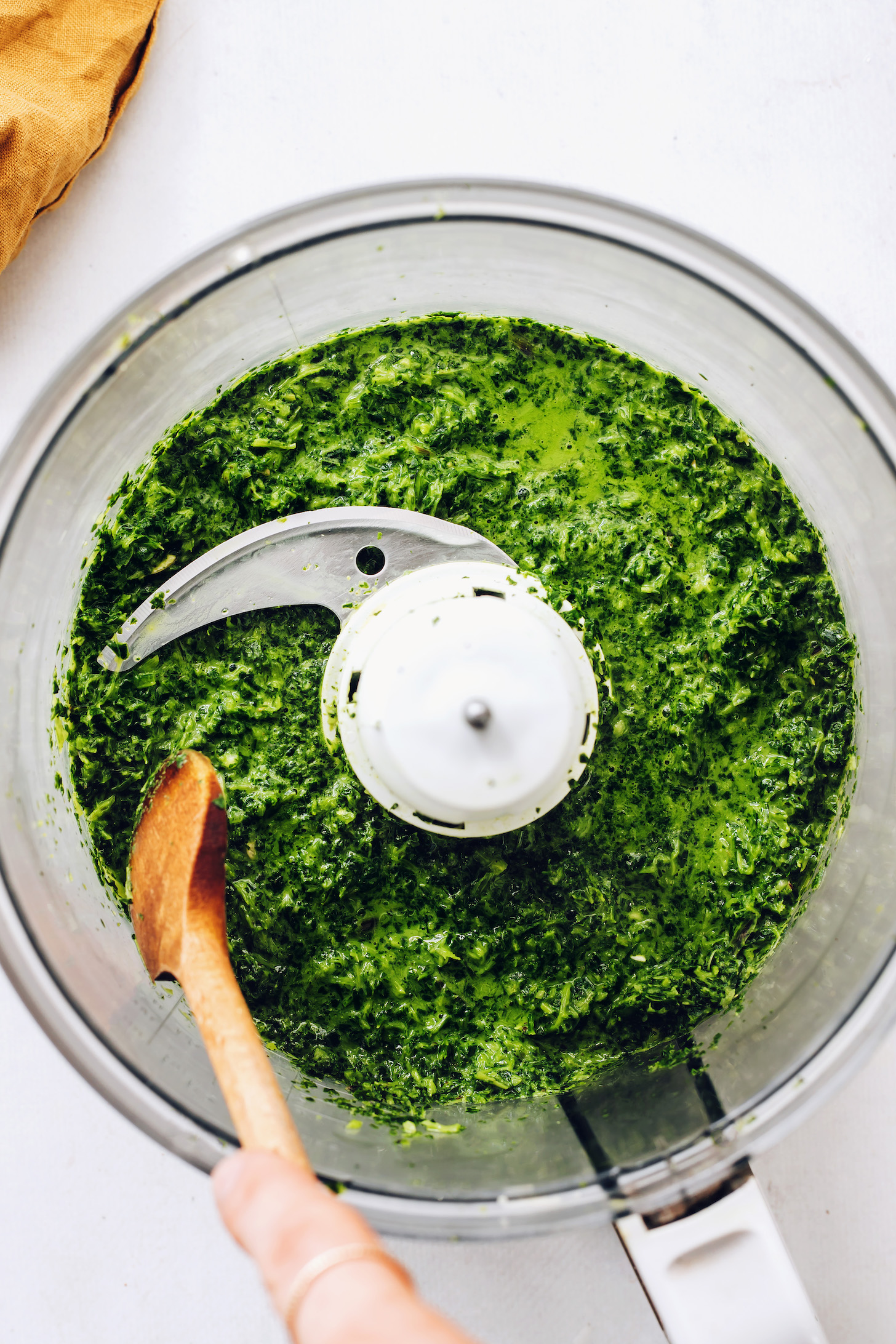 Holding a wooden spoon over a food processor of mint chutney