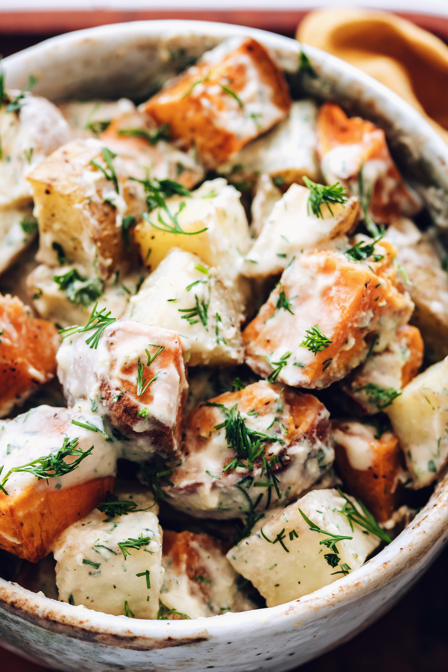 Close up shot of a bowl of roasted potato salad with dill