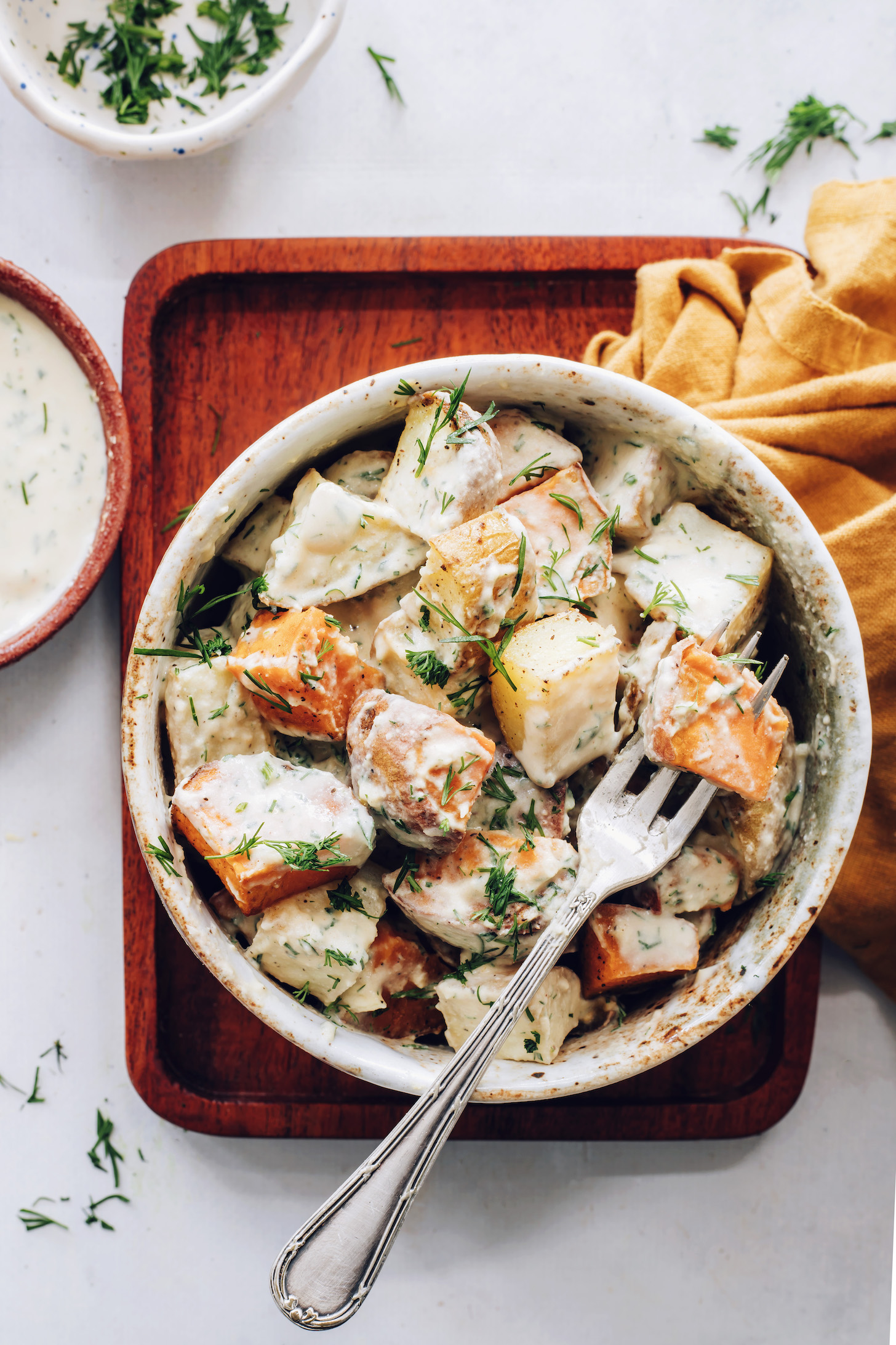Fork in a bowl of roasted potato salad with garlic dill dressing