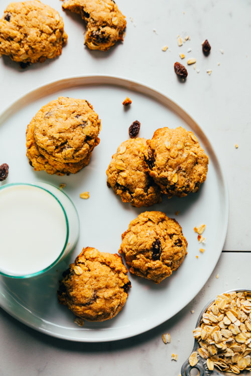 Plate of vegan oatmeal cookies next to a glass of dairy-free milk
