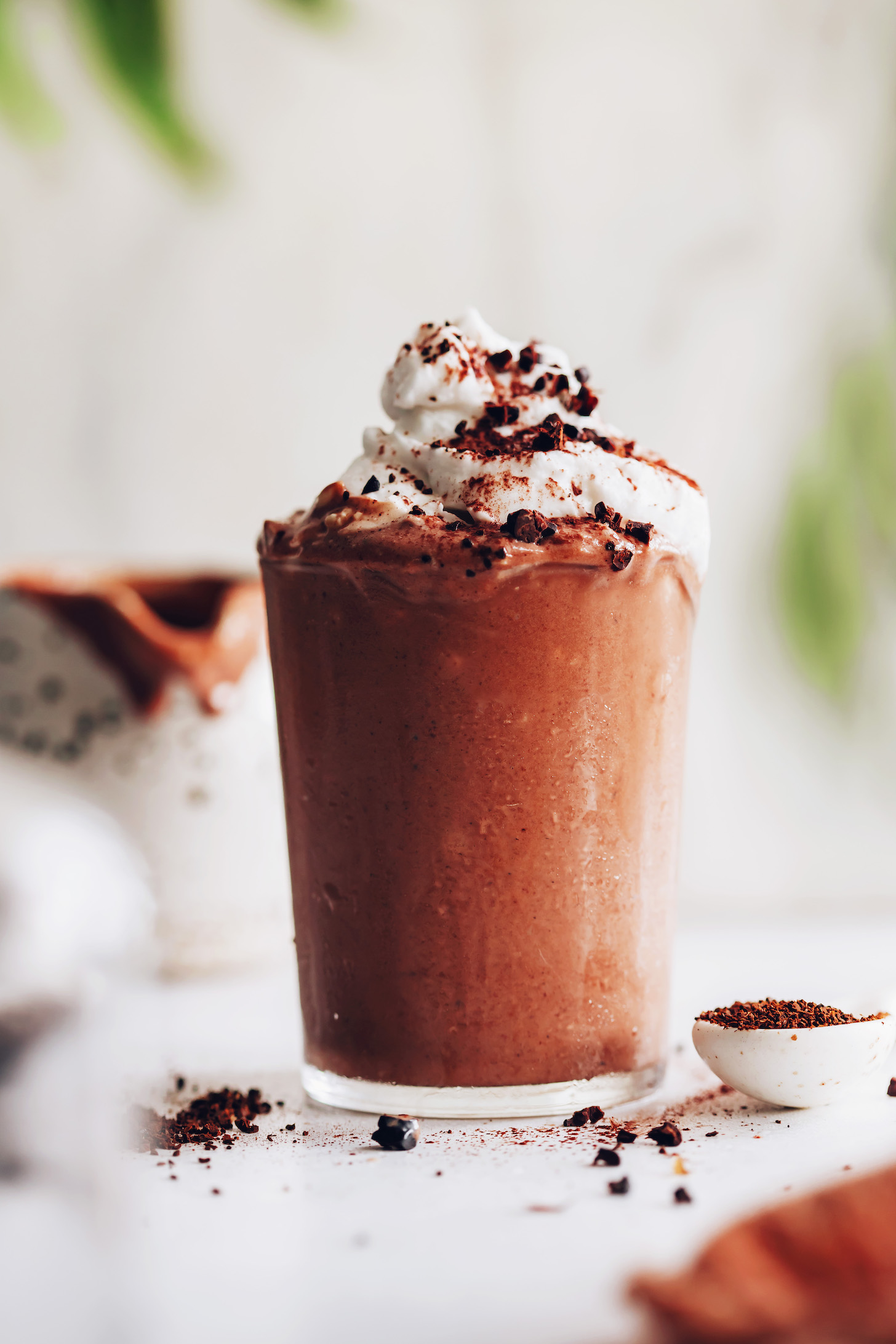 Glass of our dairy-free jamocha shake topped with coconut whipped cream and cacao nibs