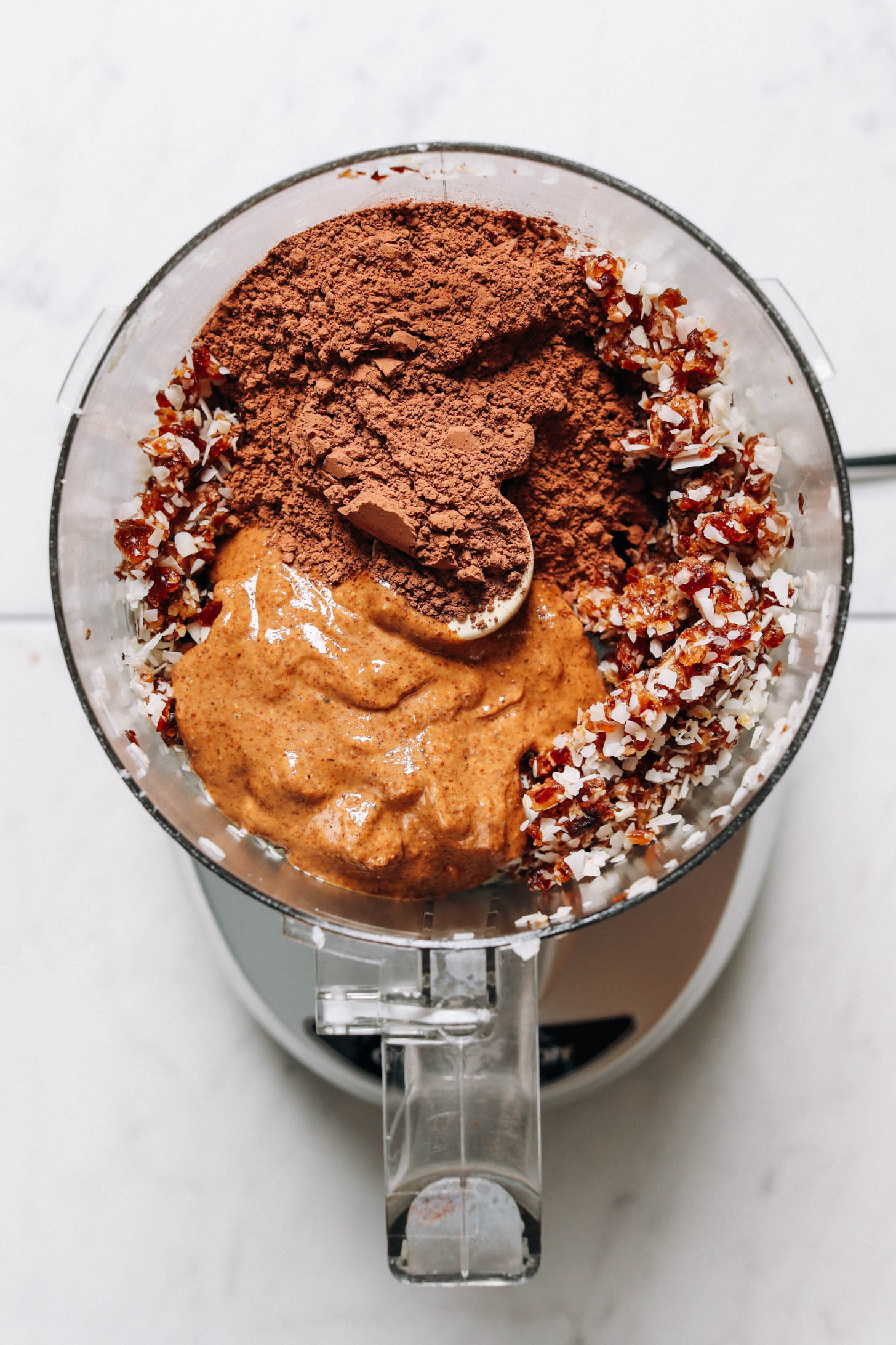 Food processor with coconut, dates, cacao powder, and almond butter