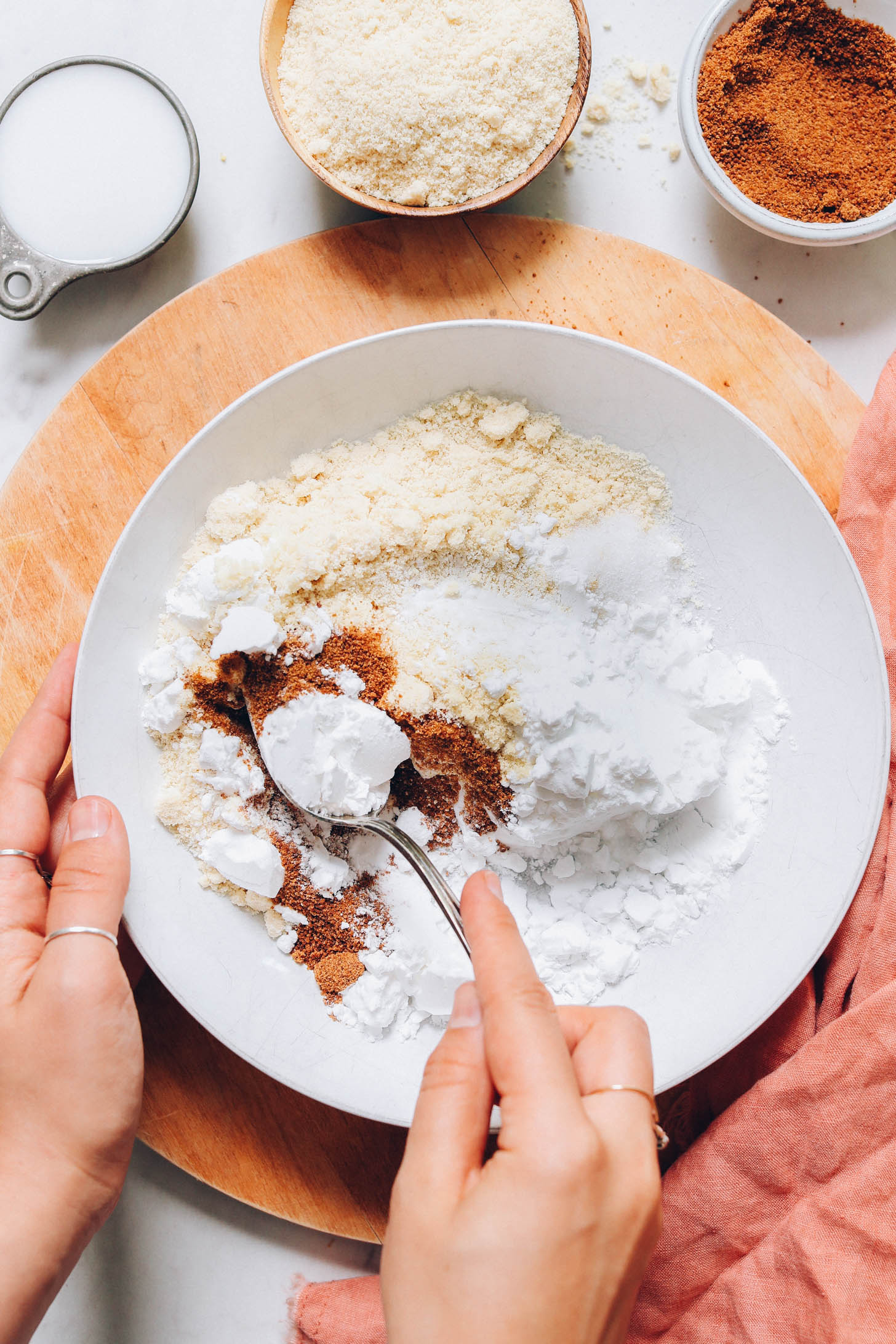 Mixing almond flour, potato starch, coconut sugar, salt, and baking powder in a bowl