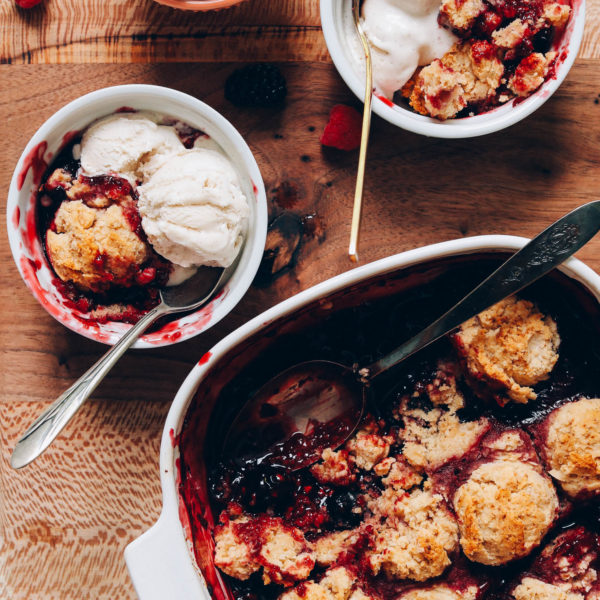 Pan and bowls of mixed berry cobbler with vanilla ice cream