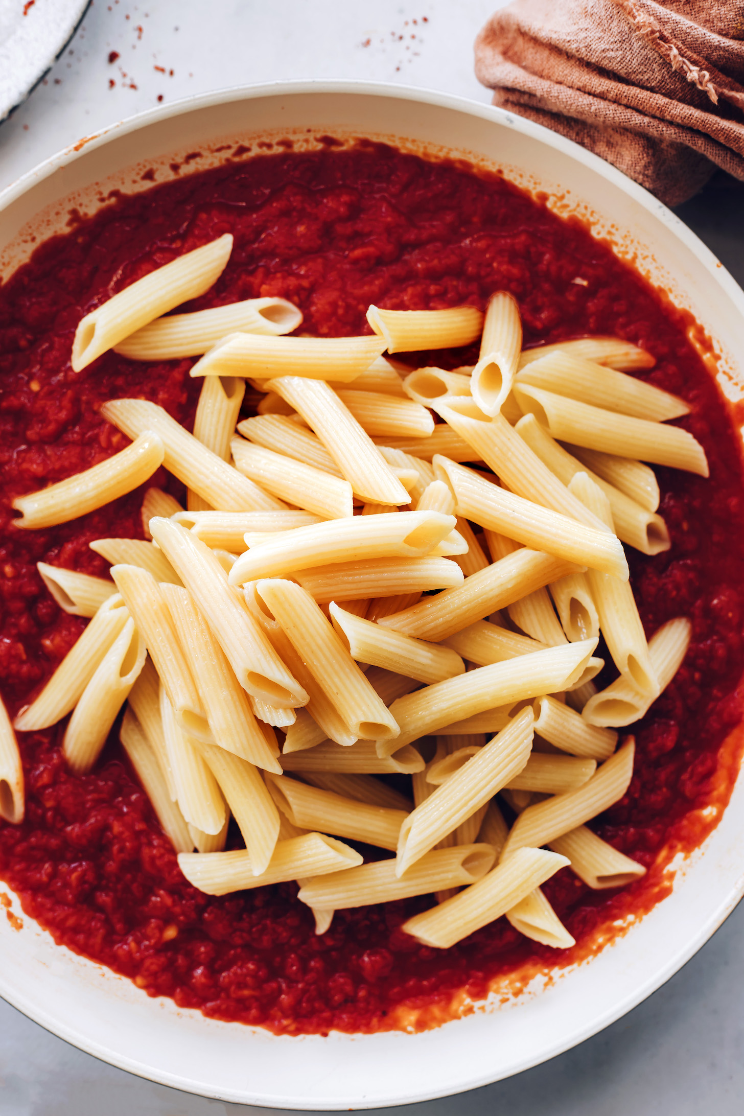 Penne noodles over a pan of arrabbiata sauce