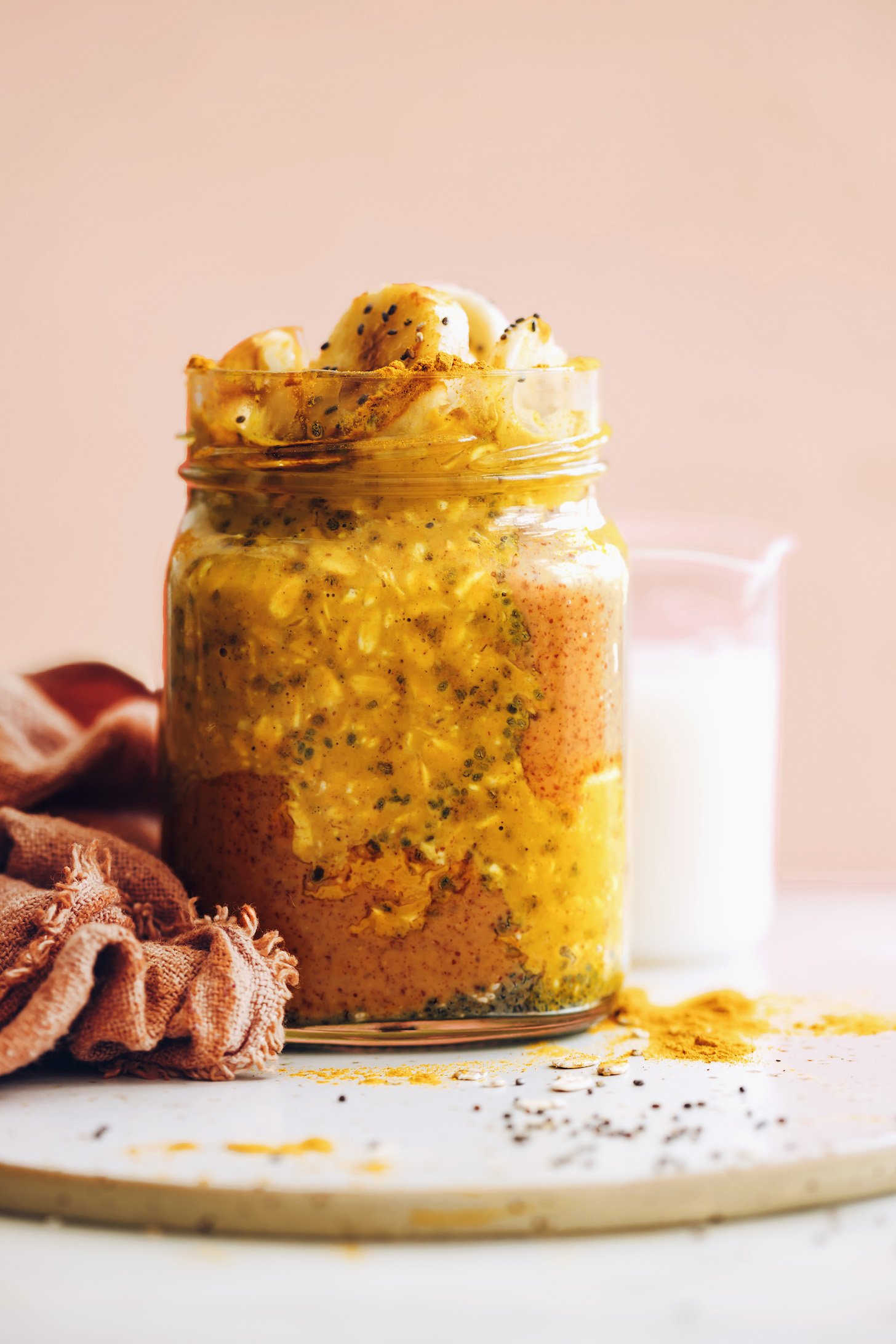 image of overnight oats infused with golden milk spices in a jar with a pink towel on the side