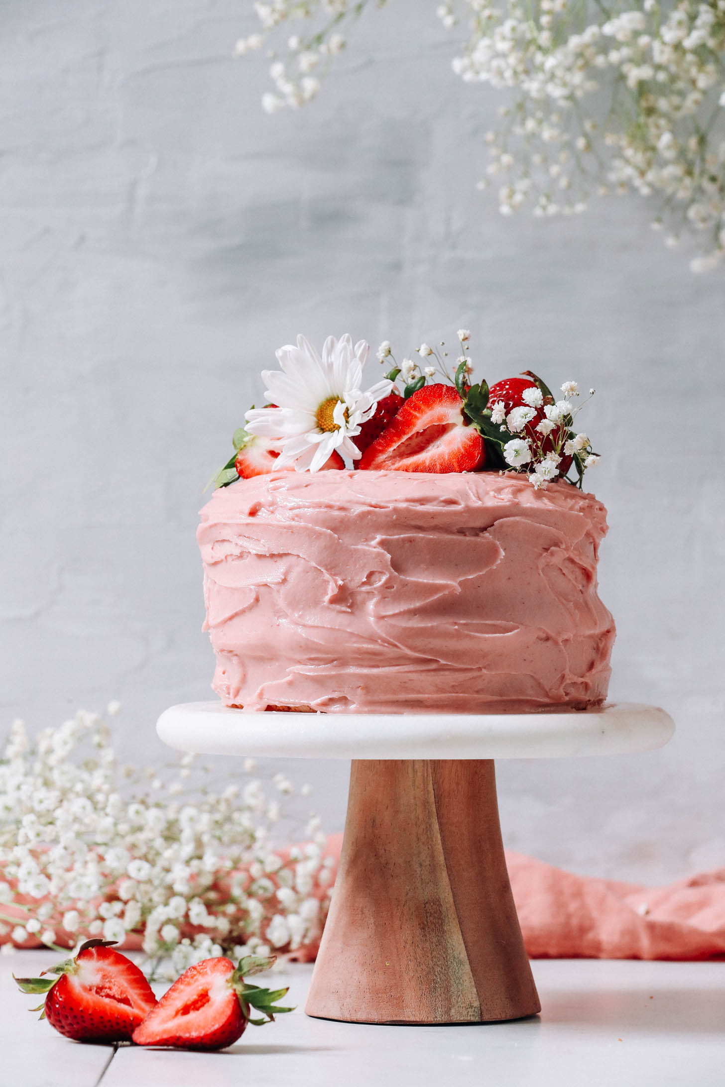 Gluten-free vegan strawberry cake decorated with fresh strawberries and flowers