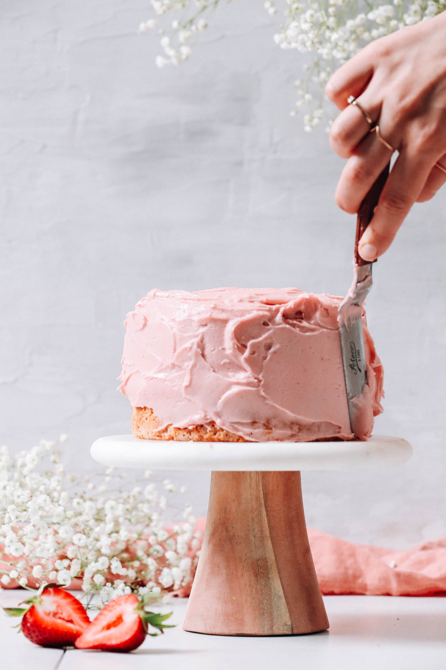 Spreading strawberry frosting on a cake