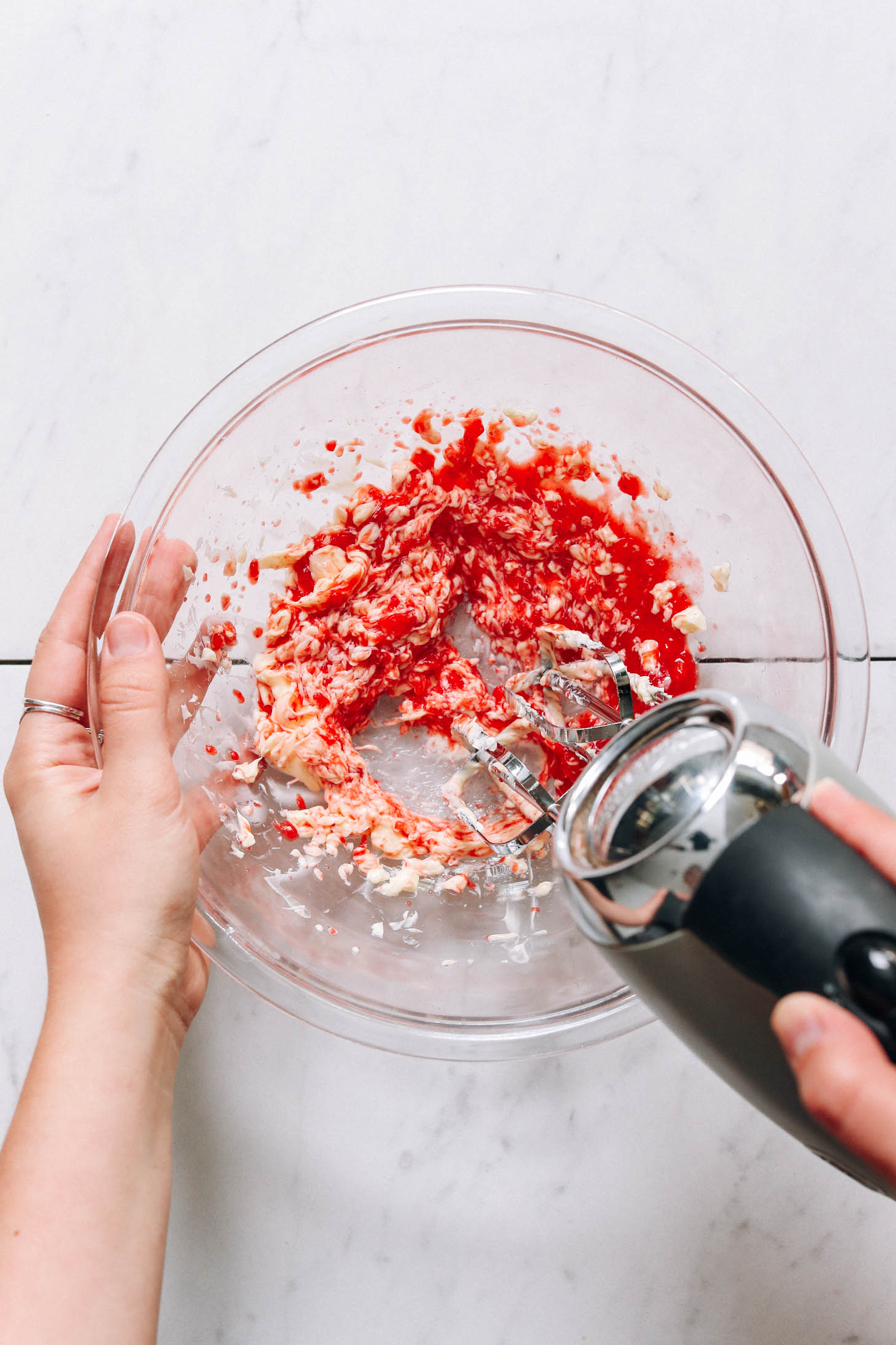 Using a hand mixer to combine strawberry purée and vegan butter