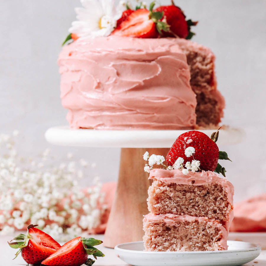Slice of vegan gluten-free strawberry cake next to the rest of the cake