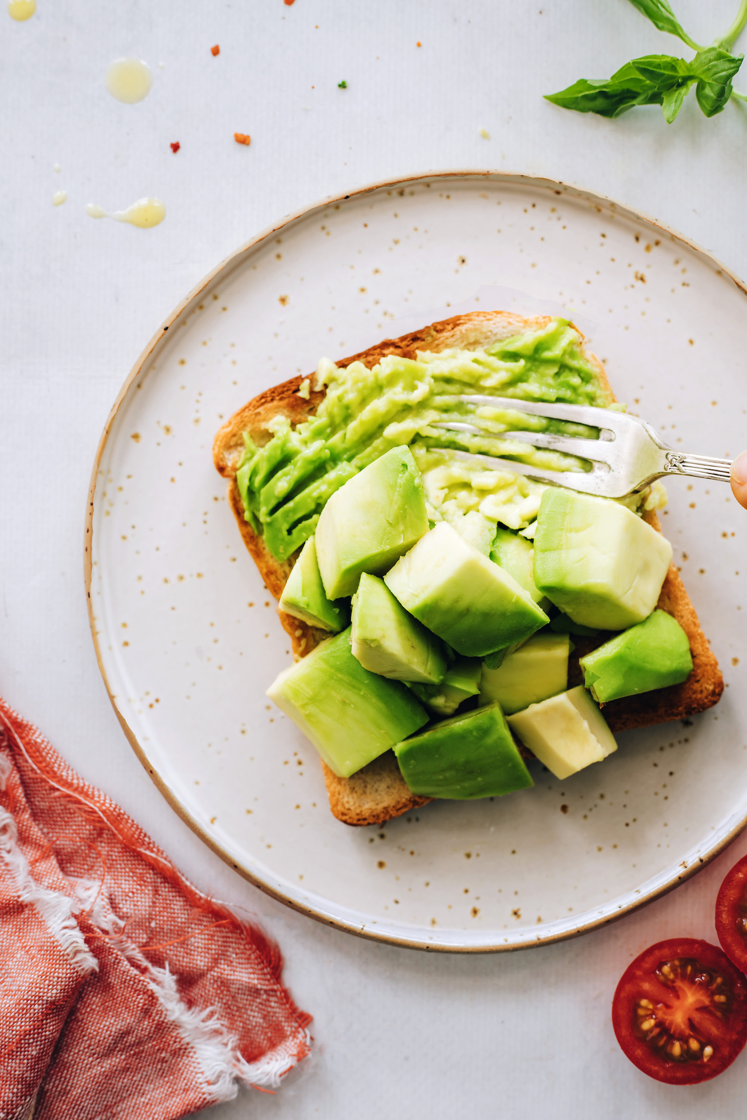 Using a fork to smash chunks of avocado on a slice of toast