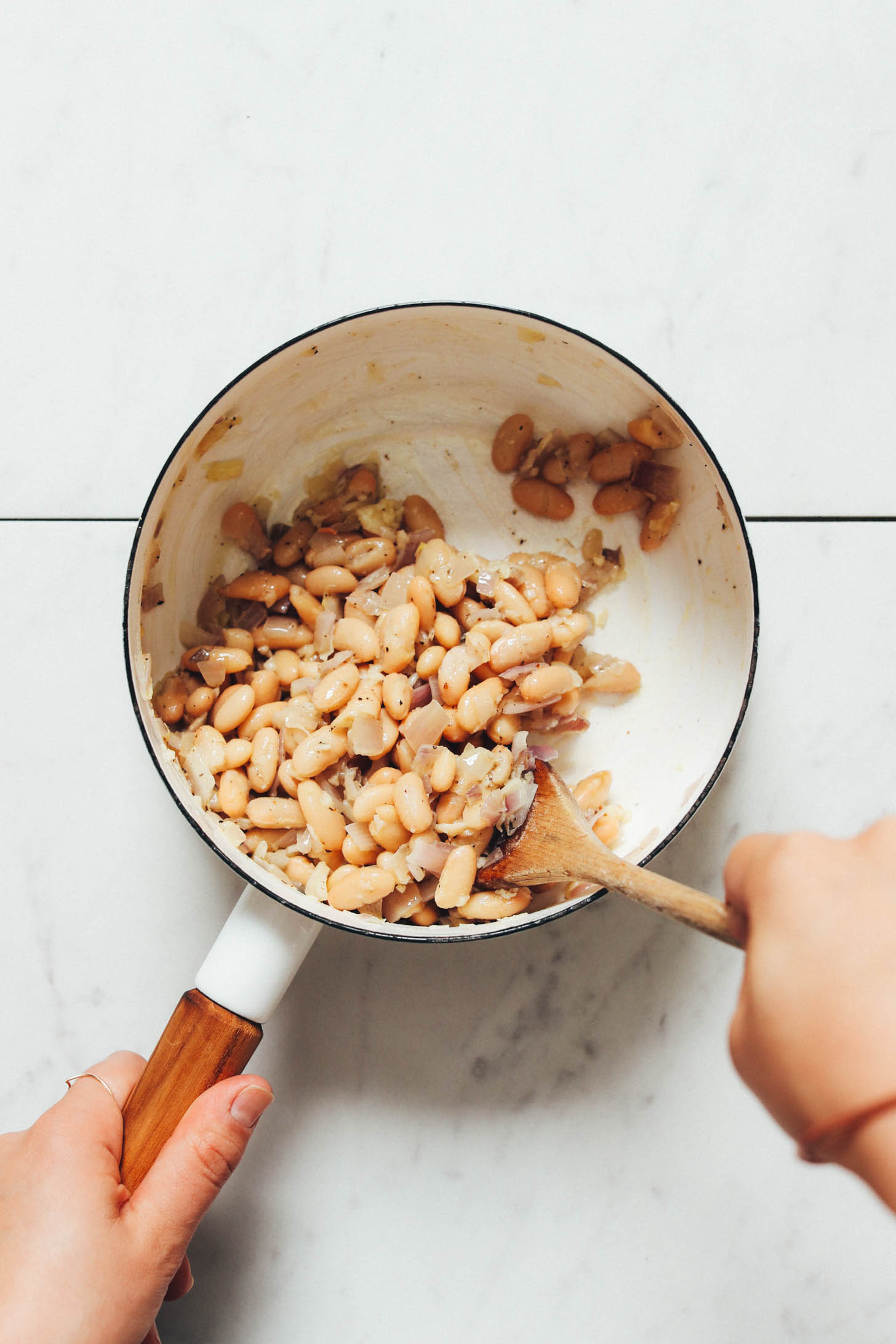 Cooking shallot, garlic, and white beans in a saucepan