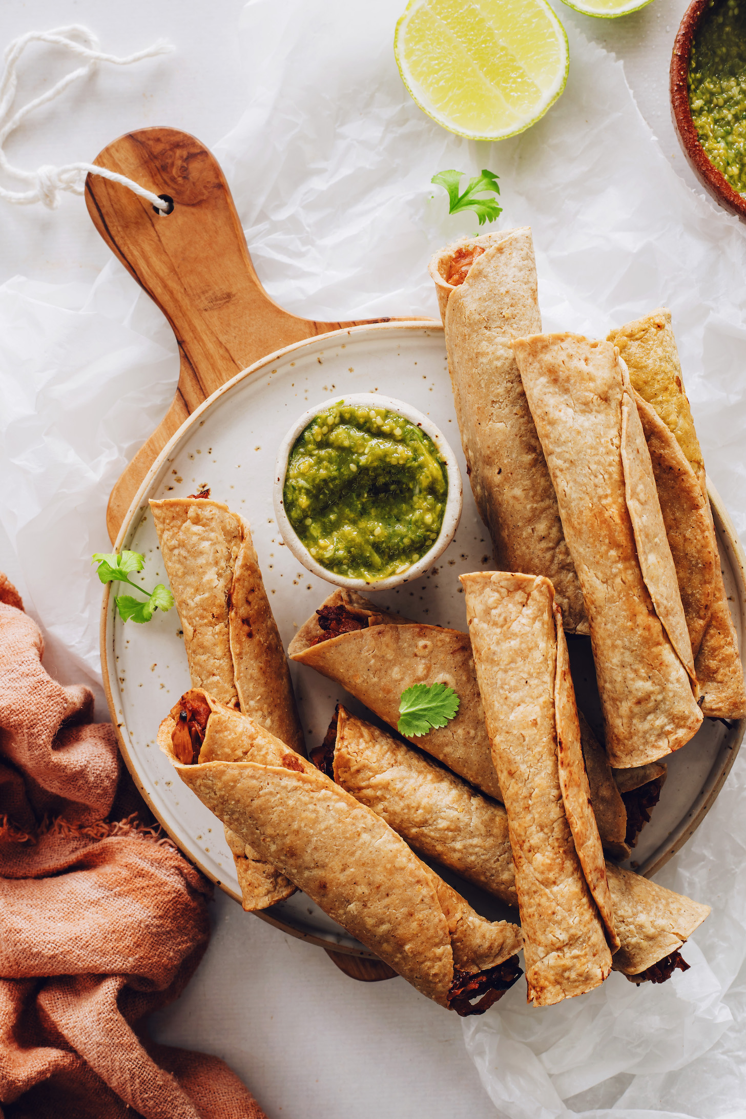 Plate of baked vegan taquitos with a bowl of tomatillo salsa
