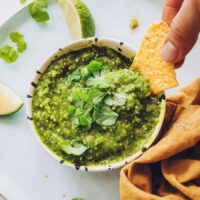 Dipping a tortilla chip into a bowl of roasted salsa verde
