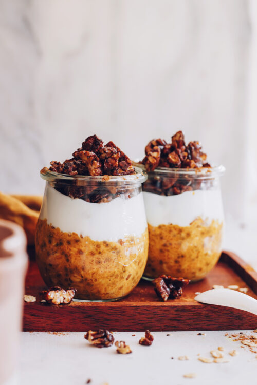 Two jars of pumpkin pie overnight oats with coconut yogurt and candied pecans