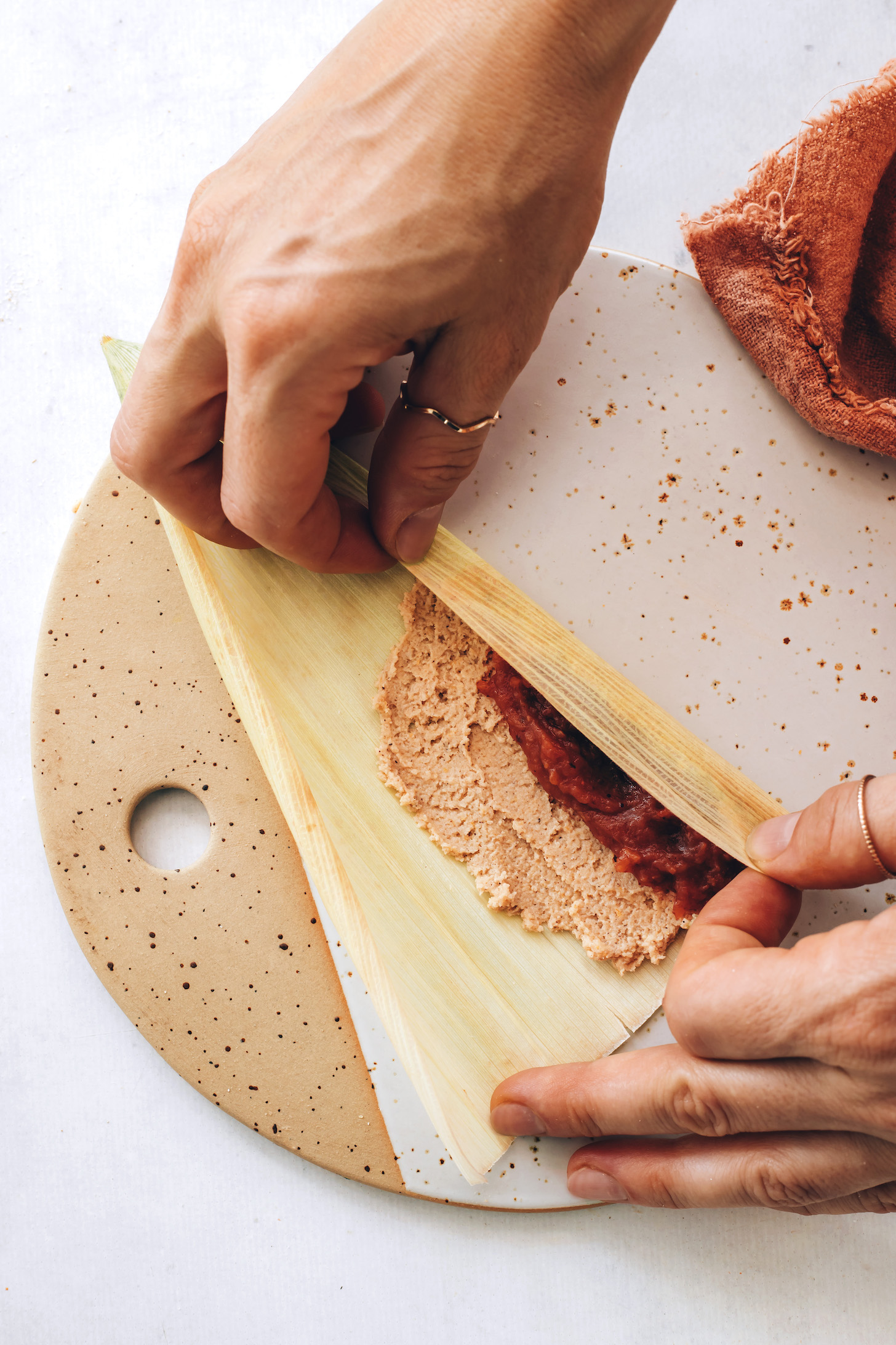 Folding a corn husk over masa filling and apple butter