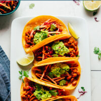 Plate of vegan and gluten-free smoky bbq bean tacos with guacamole on top