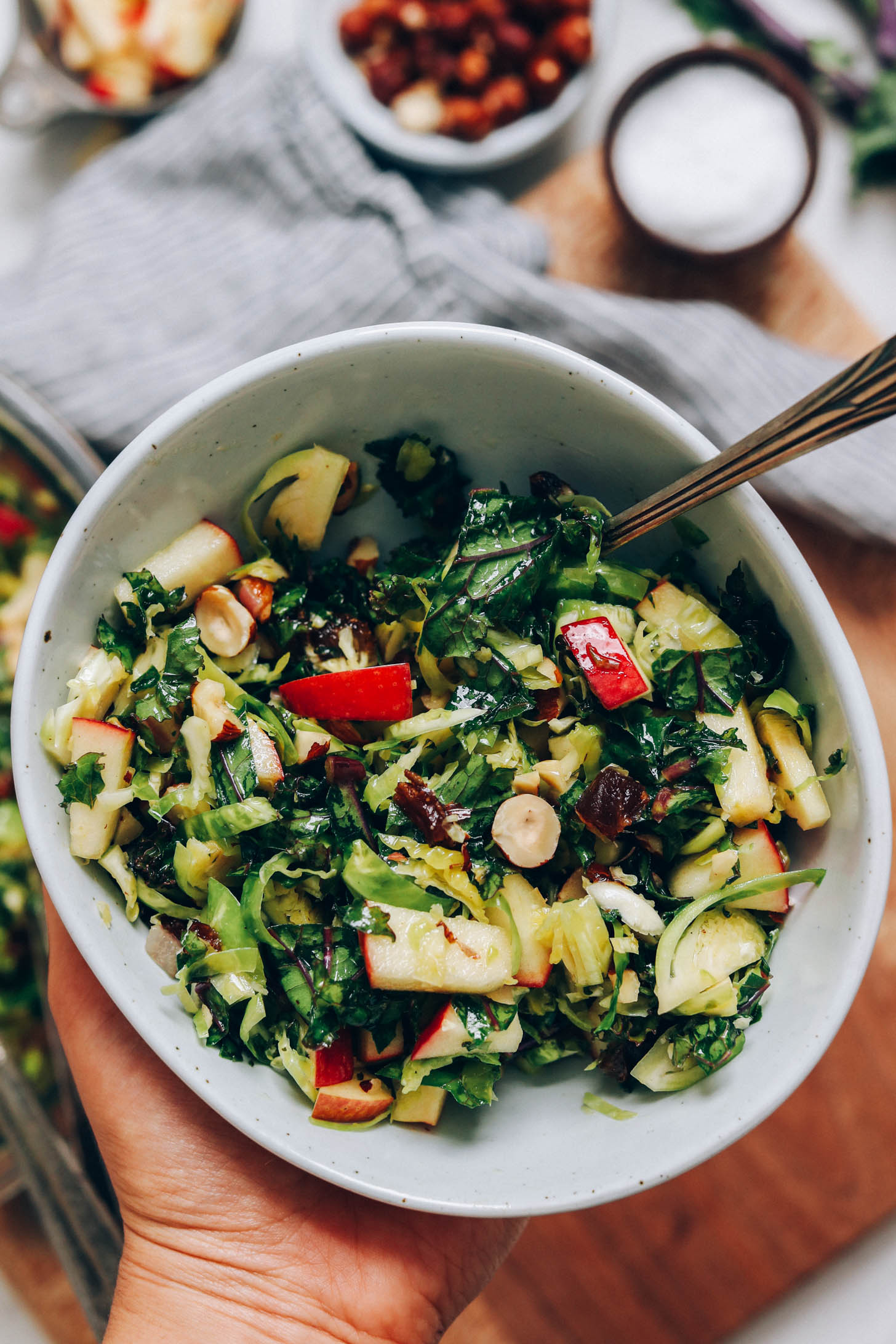 Close up shot of a bowl of brussel sprout salad with apples, dates, and hazelnuts
