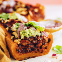 Enchilada-stuffed butternut squash topped with guacamole, cilantro, and red onion
