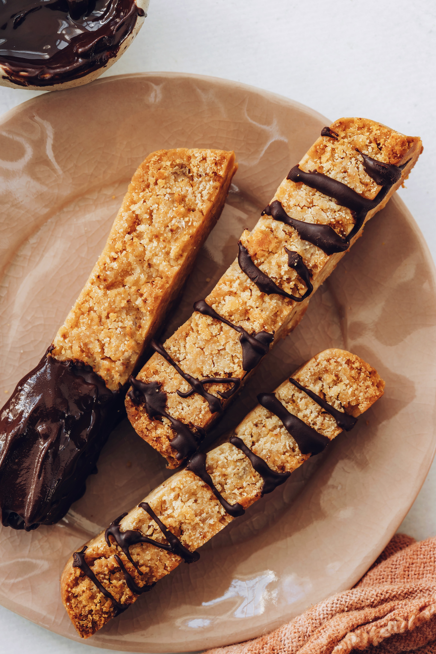 Plate of gluten-free ginger biscotti with a chocolate drizzle on dip