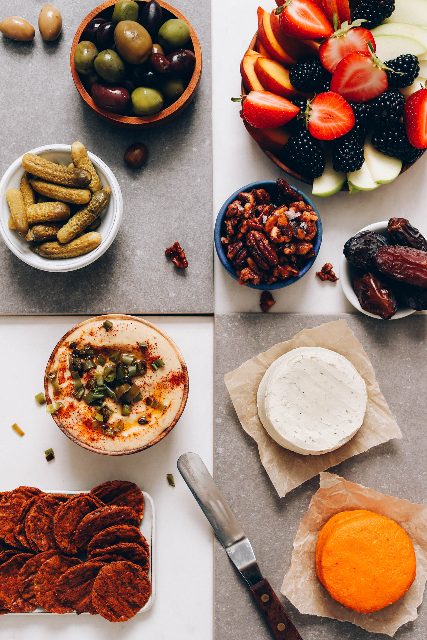 A variety of snacks for a vegan charcuterie board including fresh fruit and vegan cheese